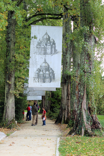 A group of kids under an archway of trees with banners hanging in the middle.