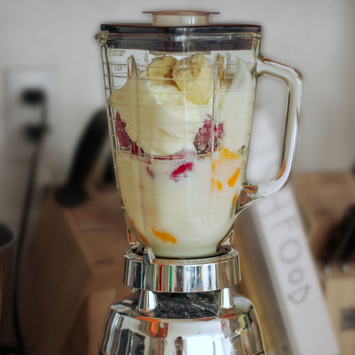 glass blender filled with fruit and yogurt for a smoothie.