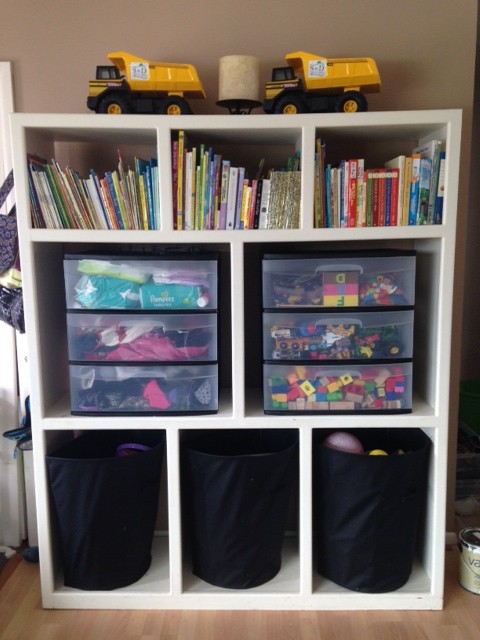 A book shelf filled with books and plastic boxes.