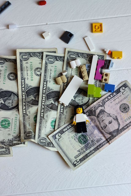 A bunch of money and lego that are on a white table.