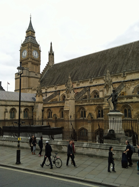 A group of people walking in front of a Parliament building.