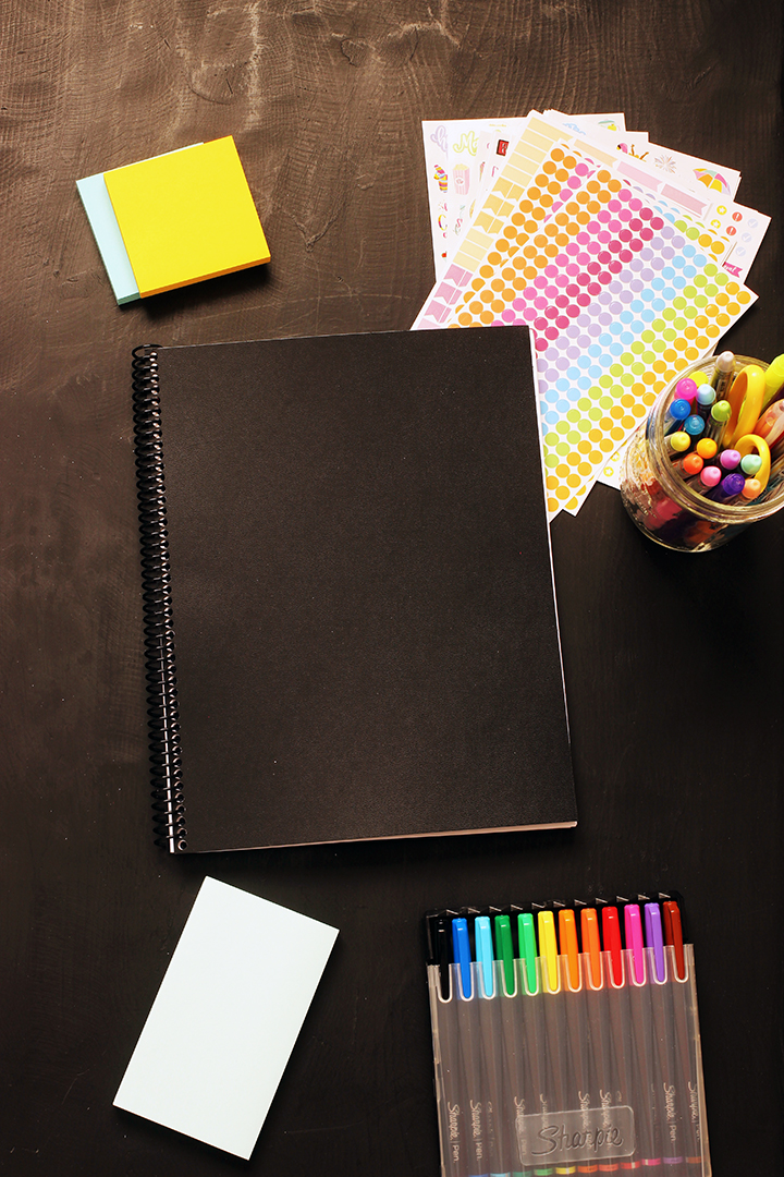 black covered planner with pens stickers and post-its