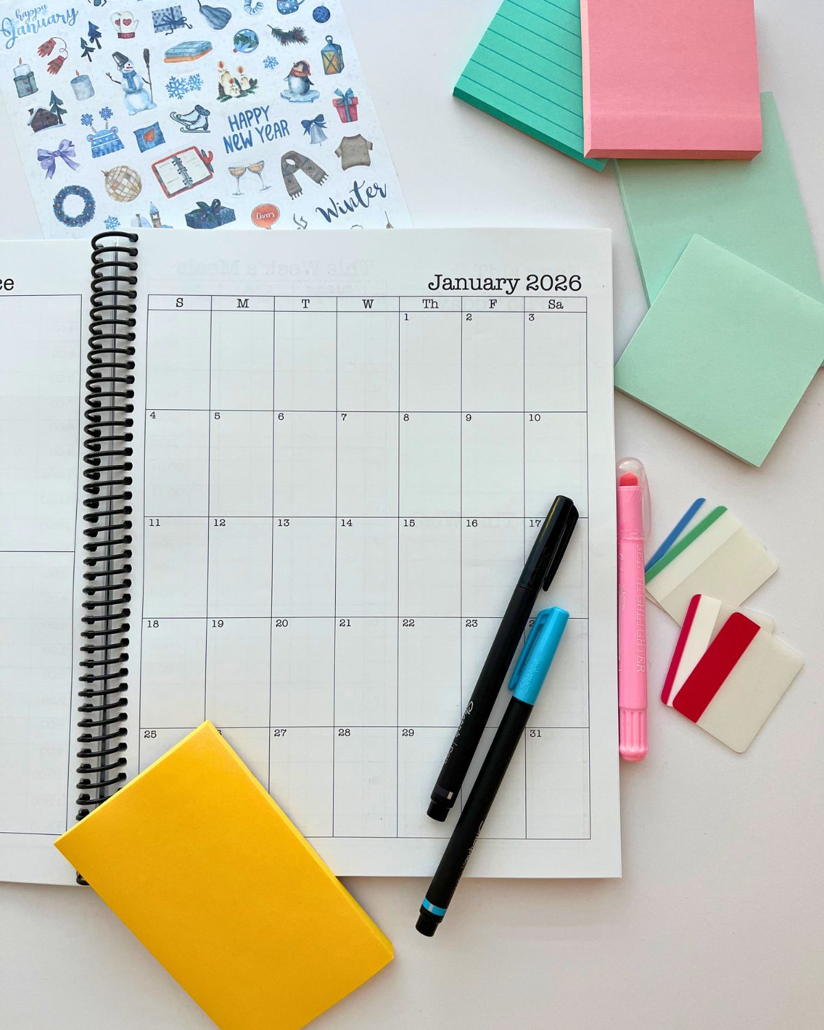 planner open to january 2026 page with pens and accessories nearby on table.