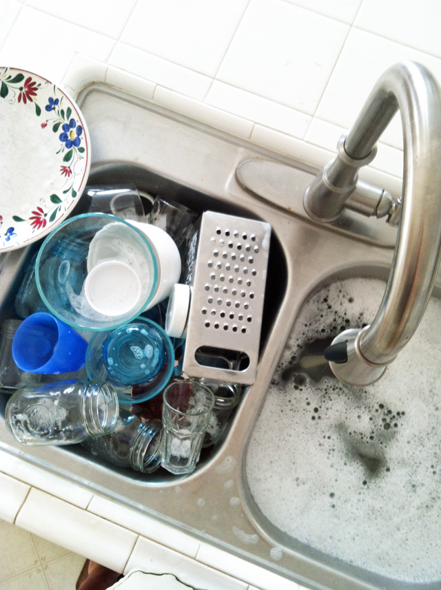 overhead shot of stainless steel sink full of washed dishes and soapy water.