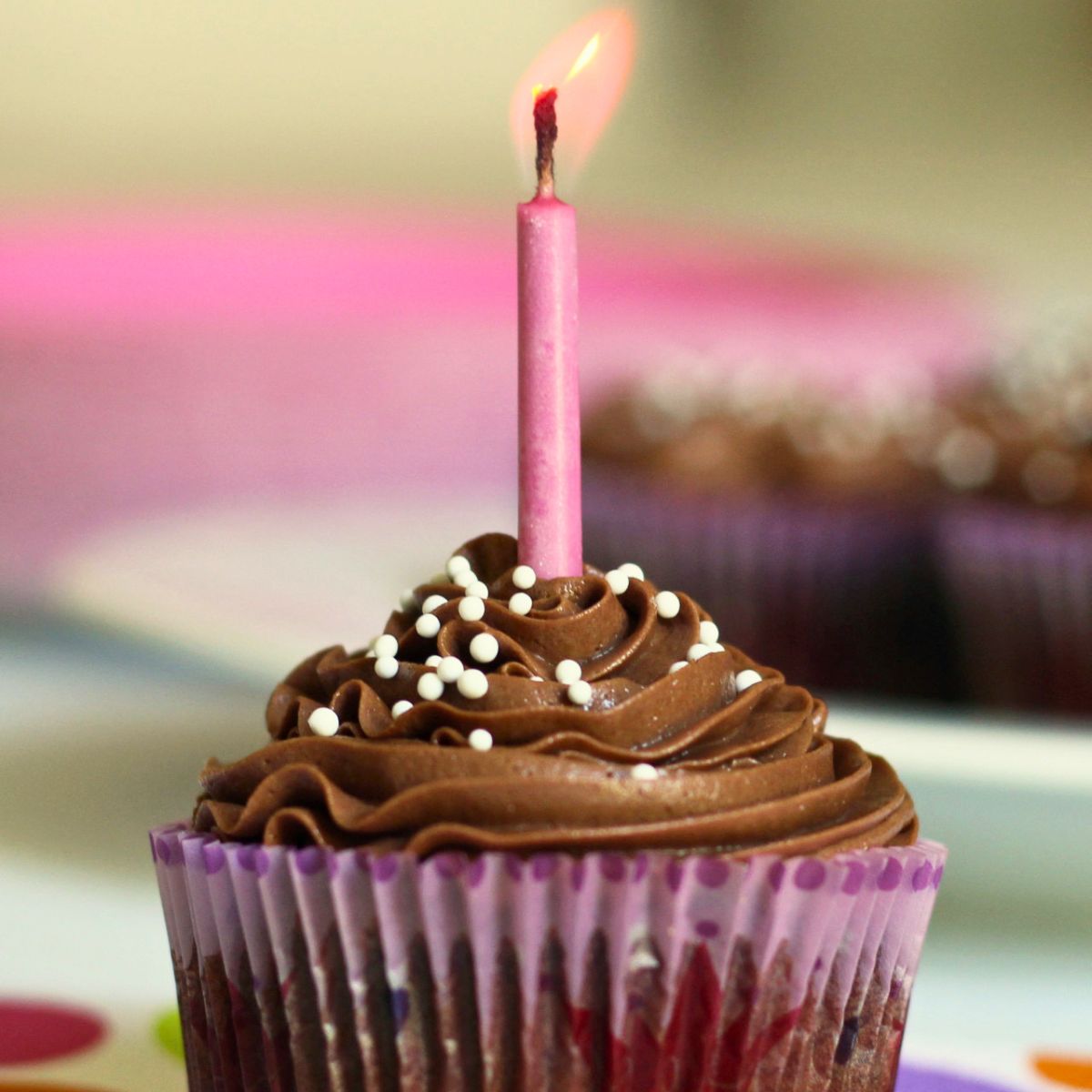 lit pink candle in chocolate frosted cupcake.