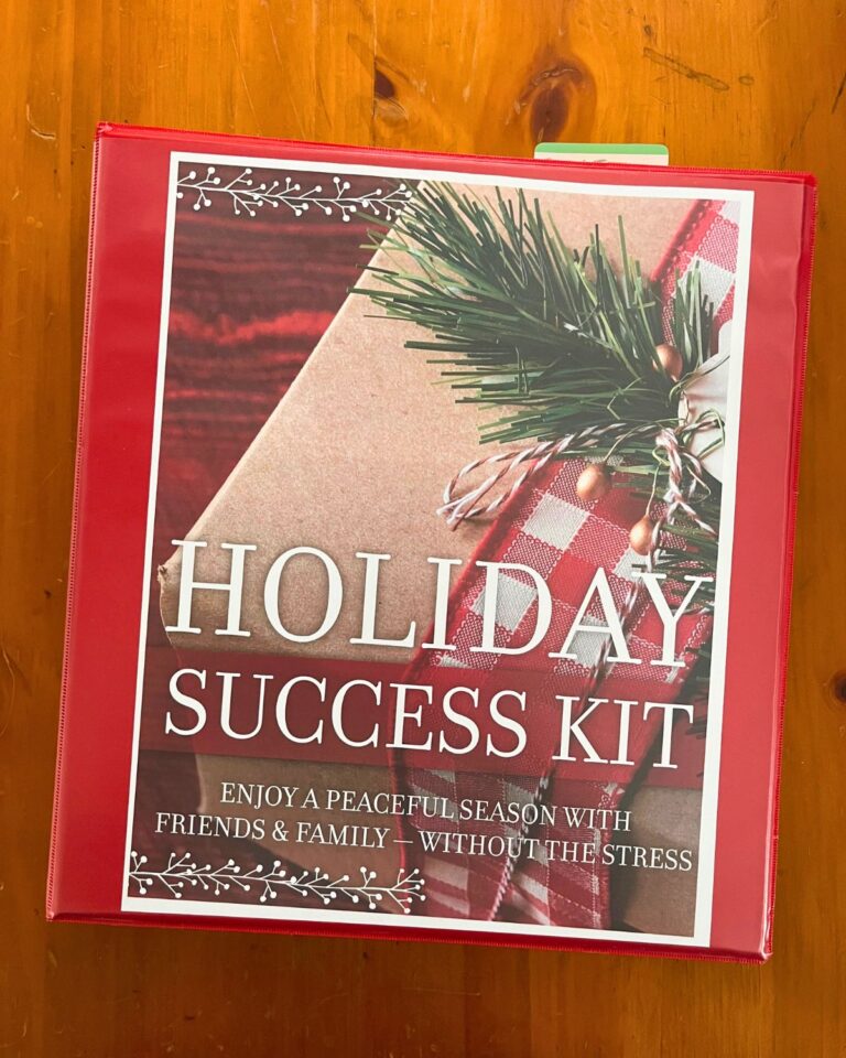 red binder housing holiday success kit on wooden surface.