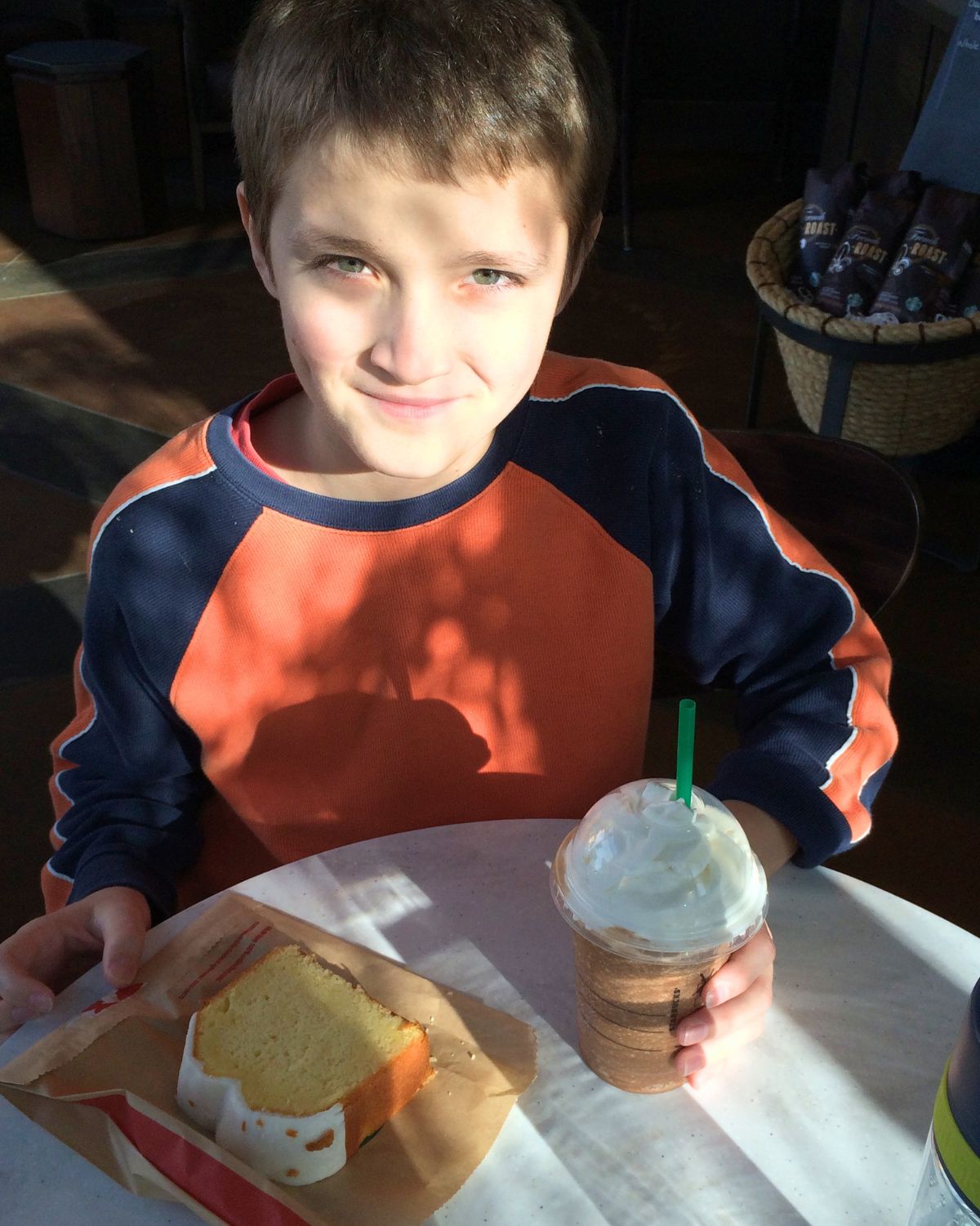 boy at starbucks with coffee and cake.