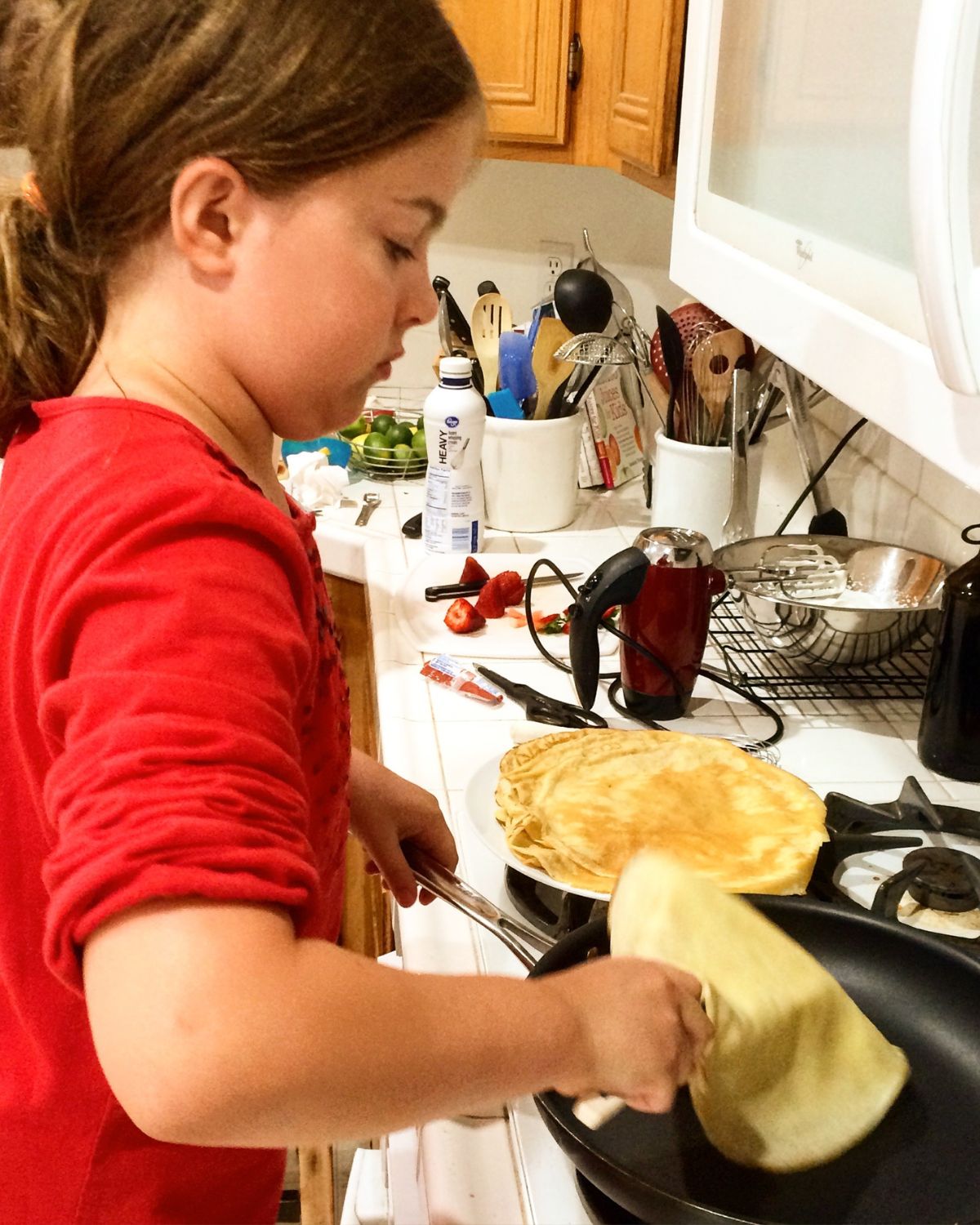 girl flipping crepes at the stove.