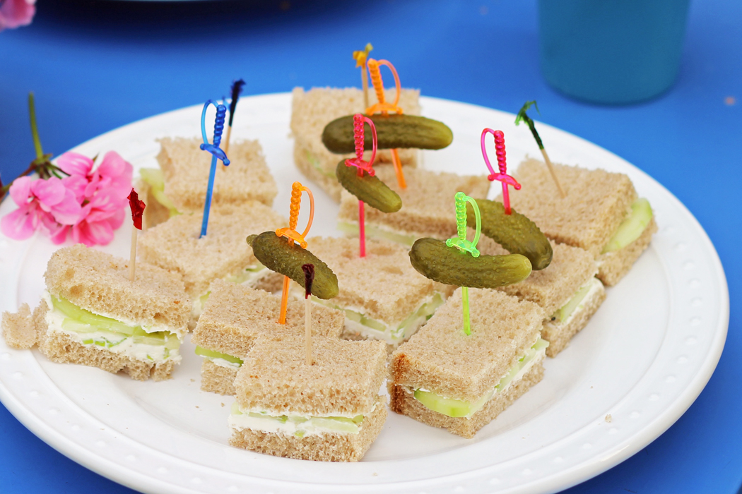 A plate of tea sandwiches with pickles on toothpicks