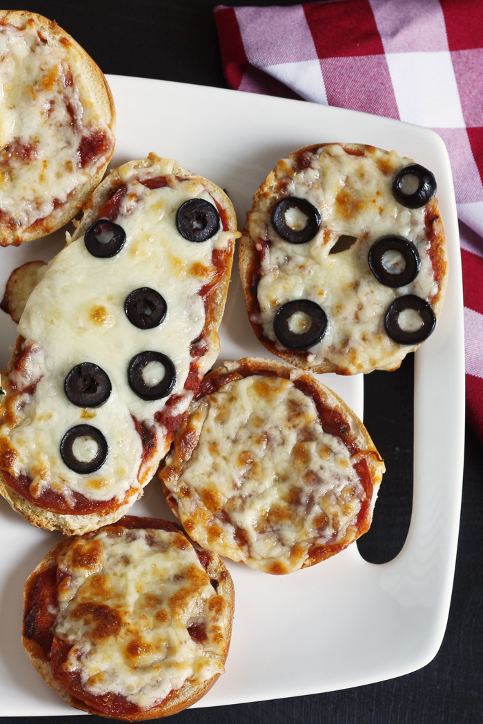 A plate of bagel and french bread pizzas