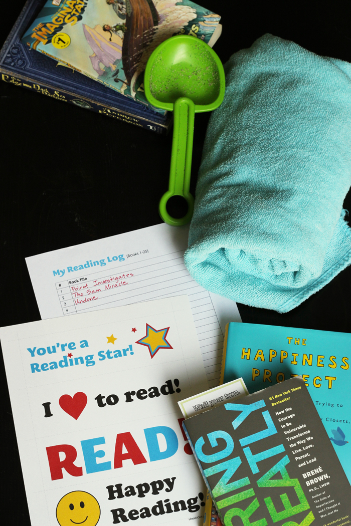 flatlay of books, beach towels, sand toys, and reading logs.