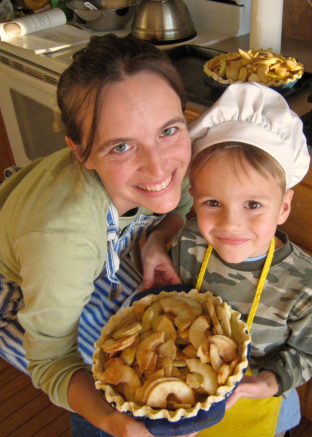 mom and boy holding apple pie they made together.