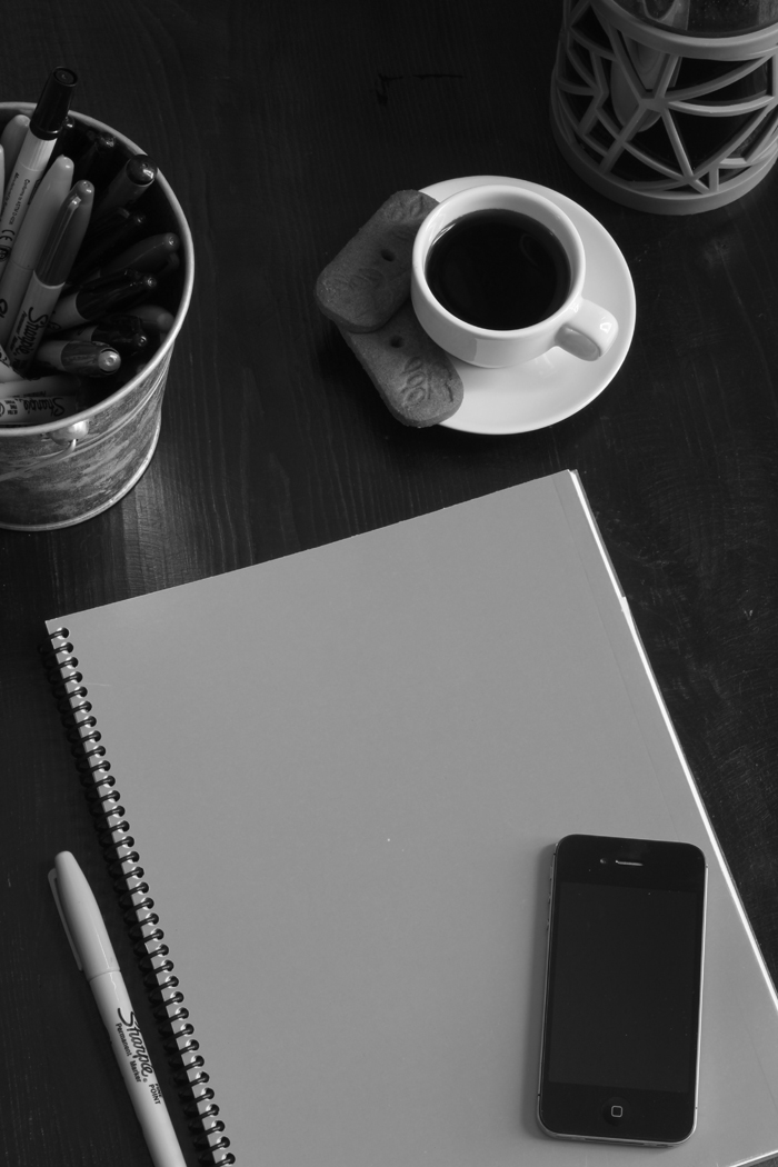 black and white planner with phone, pens, and coffee