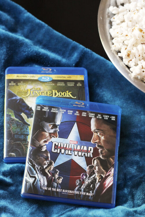 two dvds on a plush blue blanket next to a bowl of popcorn.