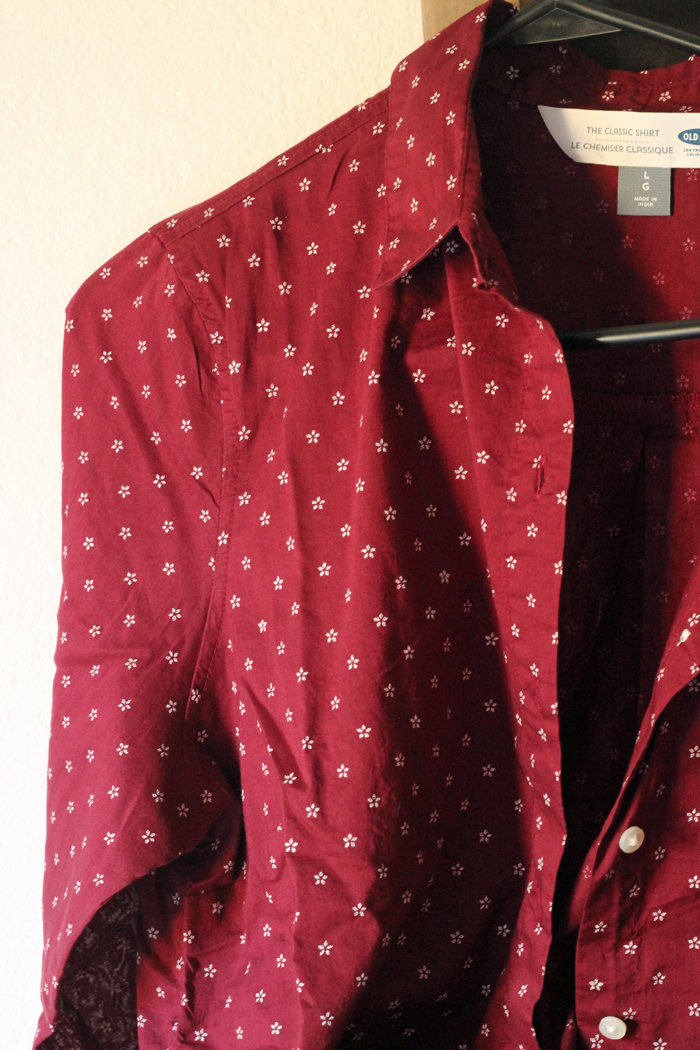 A woman\'s red blouse hanging on a hanger.