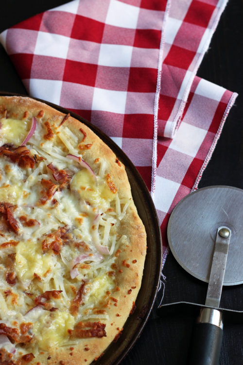 A pizza sitting on top of a table with cutter