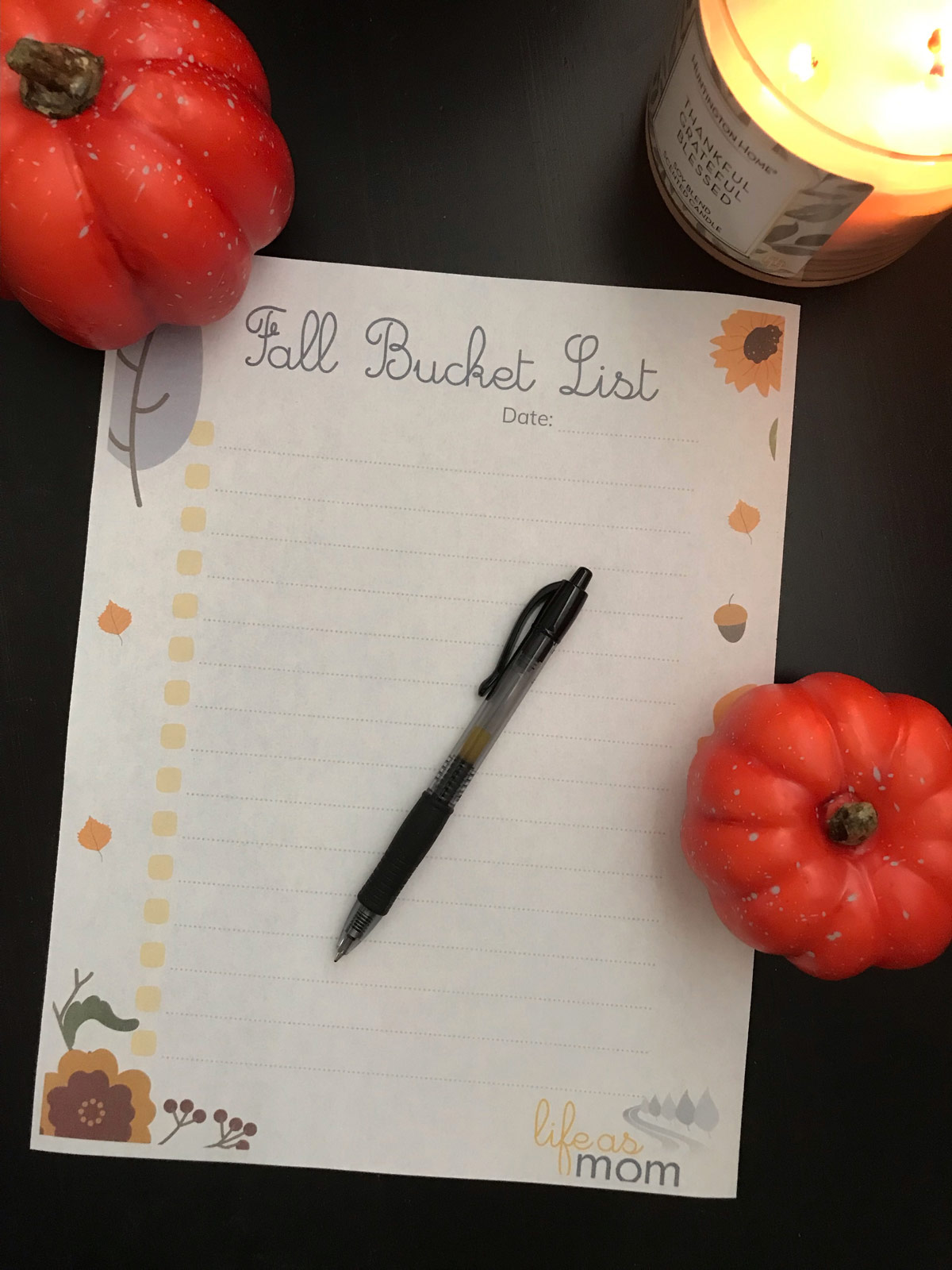 fall bucket list printable on table with small pumpkins and a lit candle.