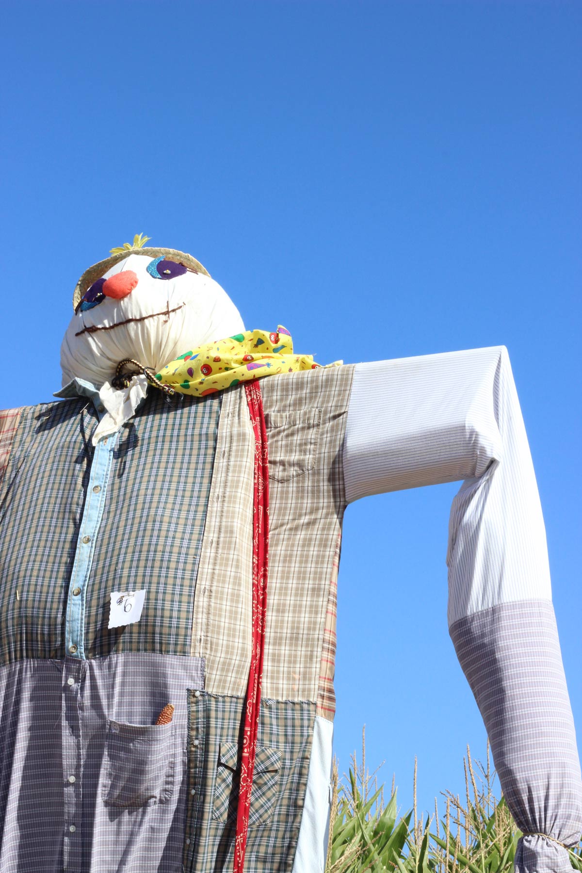 giant colorful scarecrow shown against a bright blue sky.