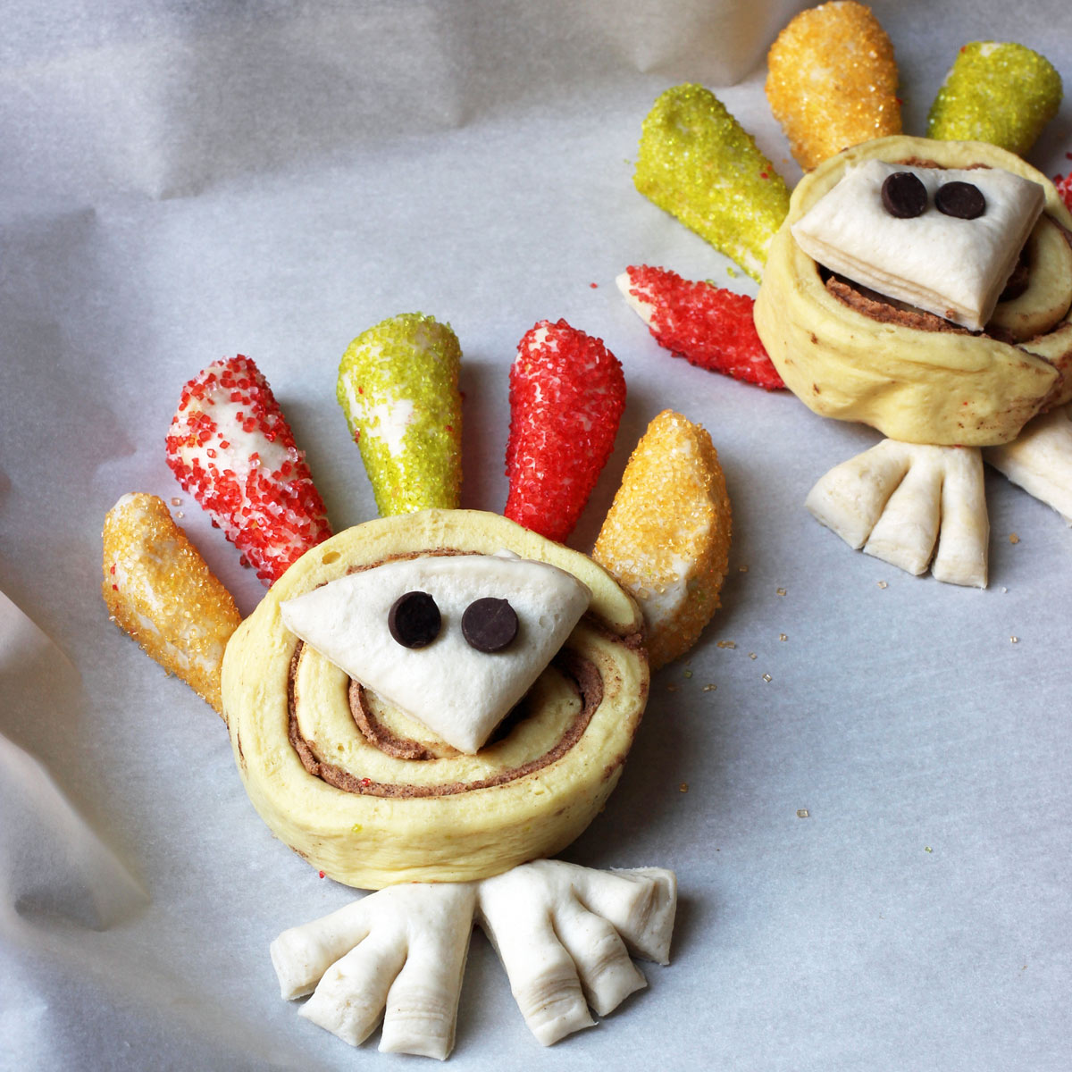 unbaked cinnamon rolls decorated like turkeys on baking sheet.