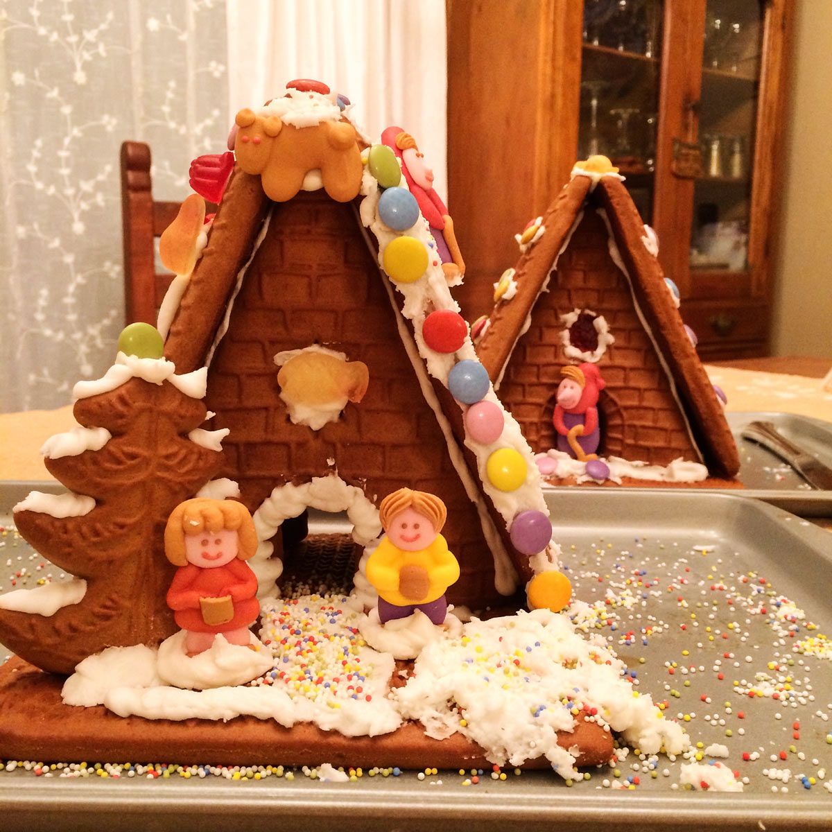 two gingerbread houses on trays on table.