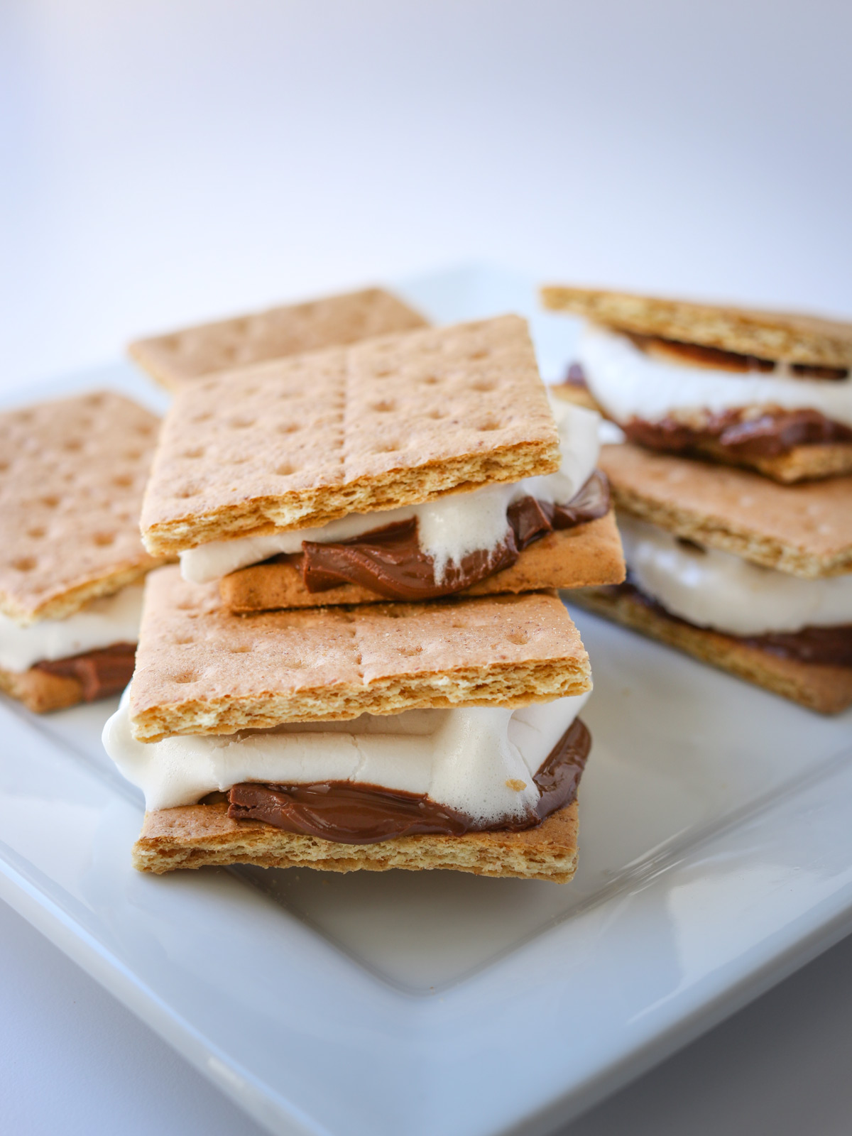 stack of cooked s'mores on a white plate on a white table.