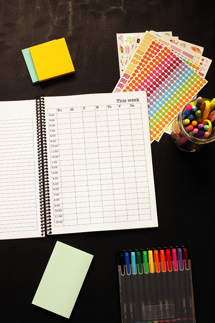 student planner open to week page with pens and post-its