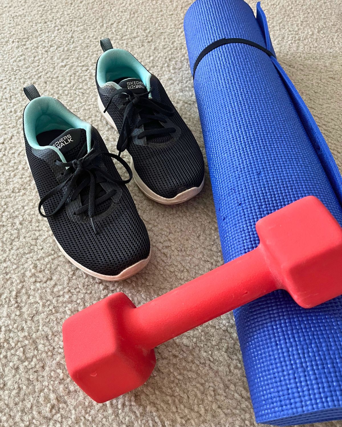 tennis shoes, dumbbell, and exercise mat on carpeted floor.