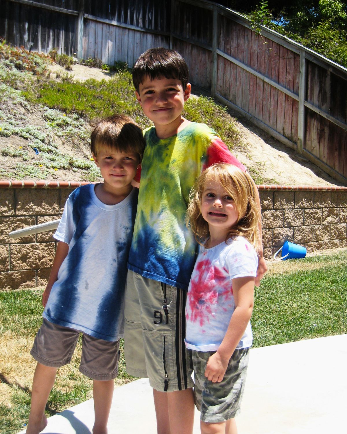 two boys in a girl wearing shorts and tie-dye t-shirts.
