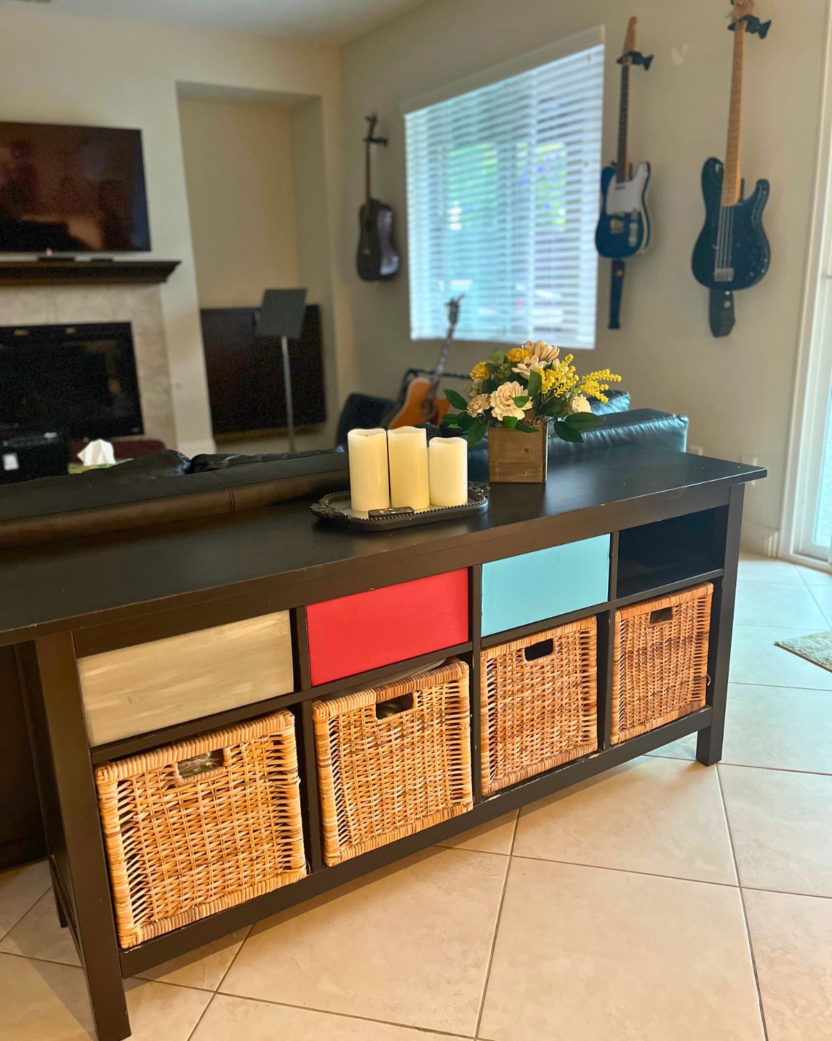 sofa table with three new boxes and guitars on walls.