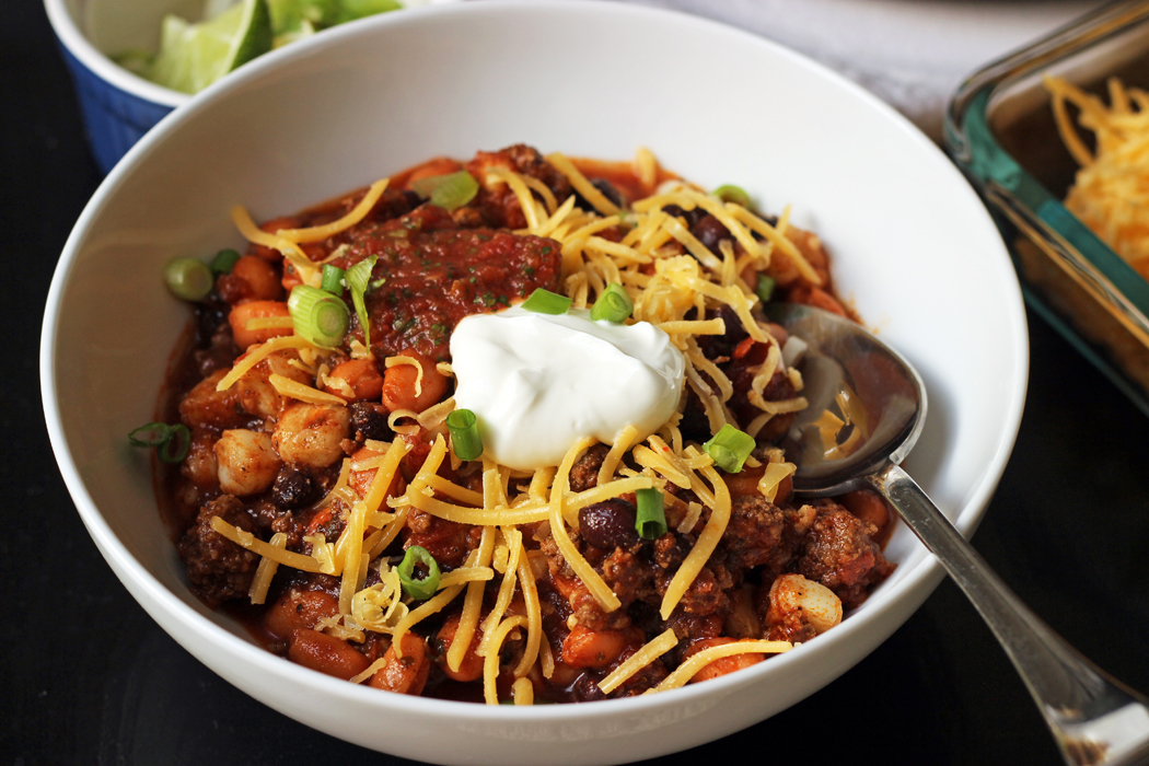 A bowl of chili with cheese and other toppings