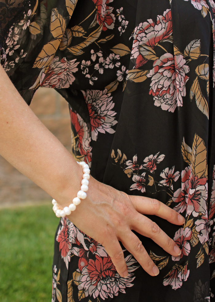 woman's arm with pearl bracelet against black kimono
