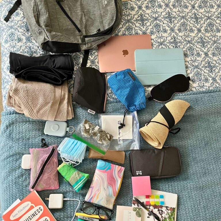 array of travel gear laid out on bed for backing.