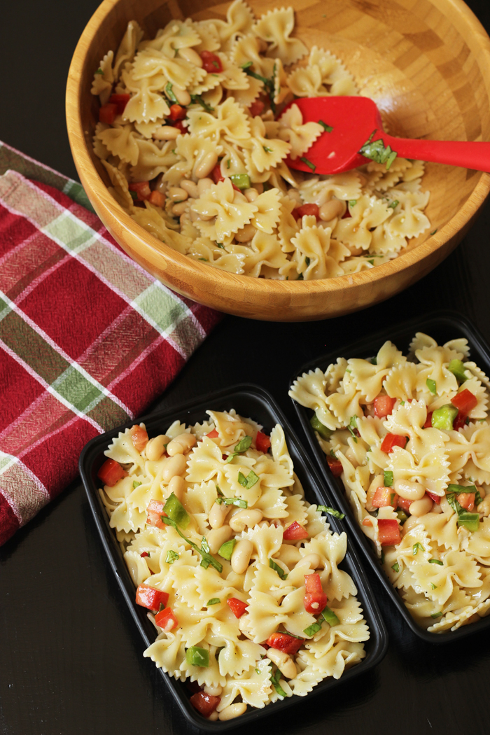 A bowl and meal prep boxes filled with bowtie pasta salad 