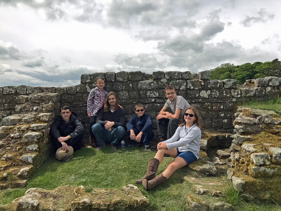 A group of kids sitting near part of Hadrian\'s wall.