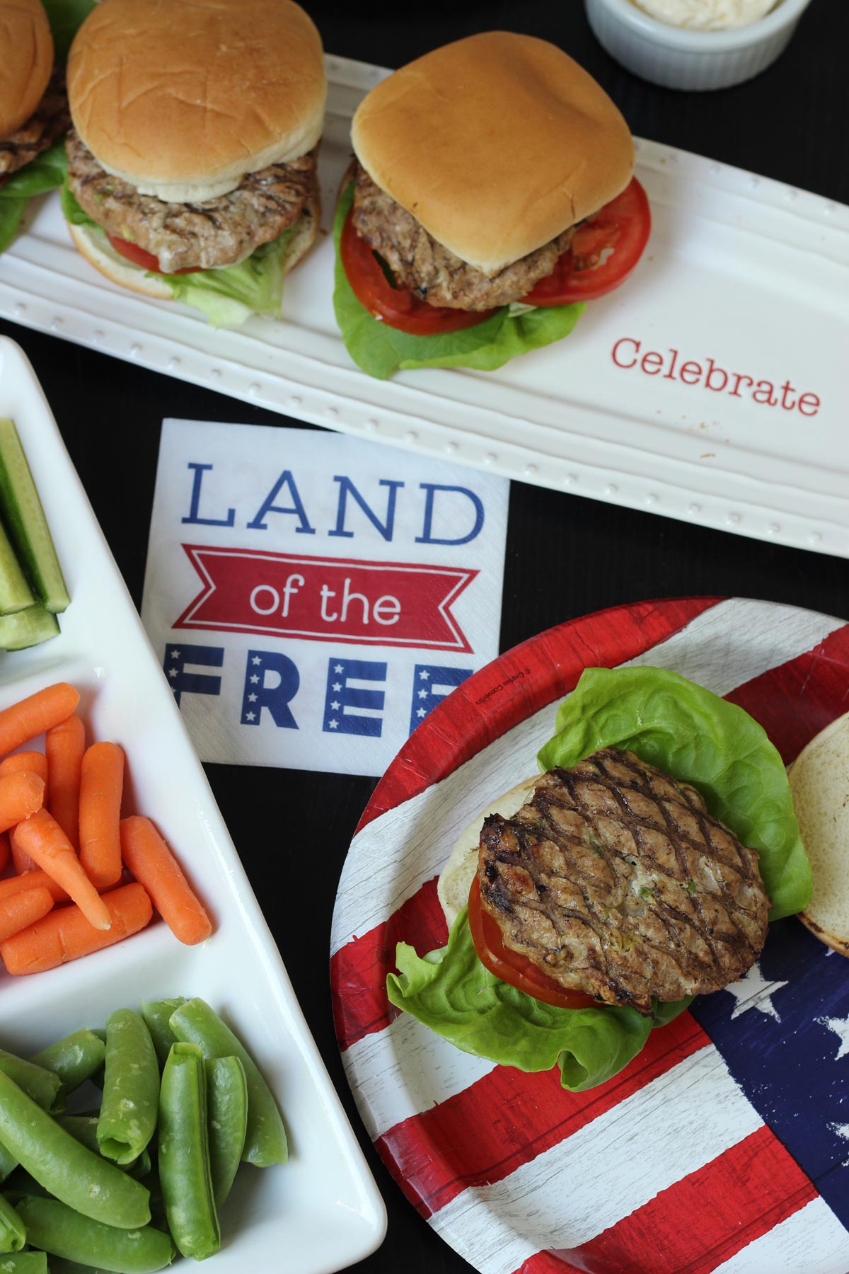 festive 4th of July table set with burgers and patriotic tableware.