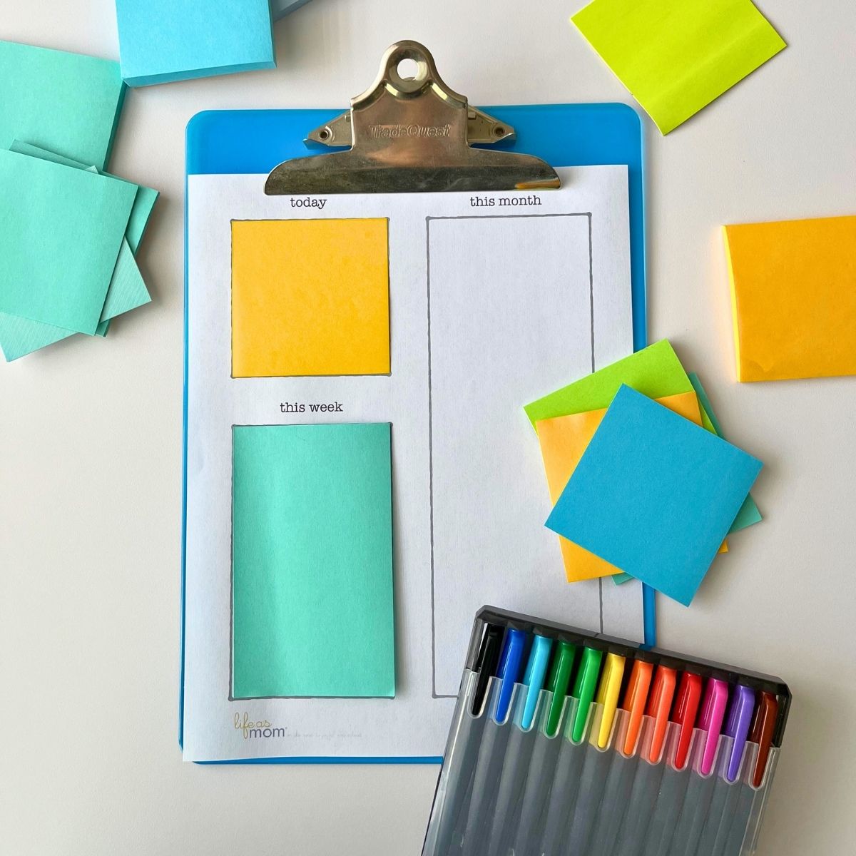 clipboard with post-it note to-do list and array of post it notes and markers.