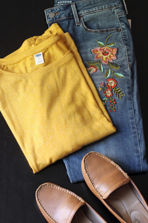 A pair of shoes with yellow sweater and embroidered jeans.