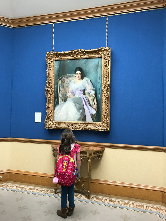 A little girl standing in front of a painting in a museum in Bath.