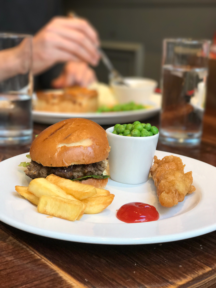 A person sitting at a table with a plate of food, at a pub