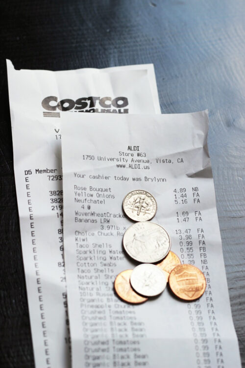 Grocery receipts and coins on black table.