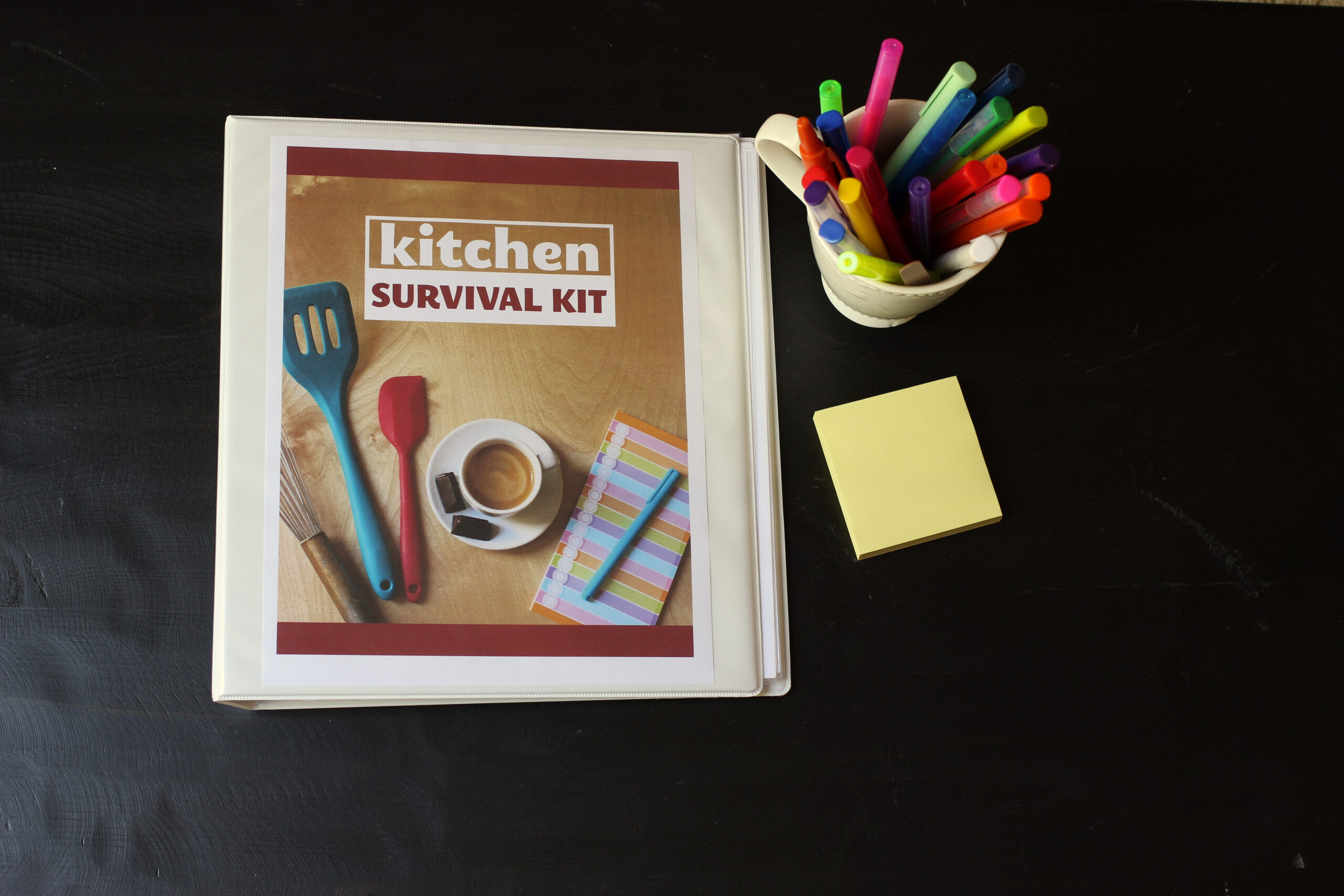 kitchen survival kit binder next to pens and post-its