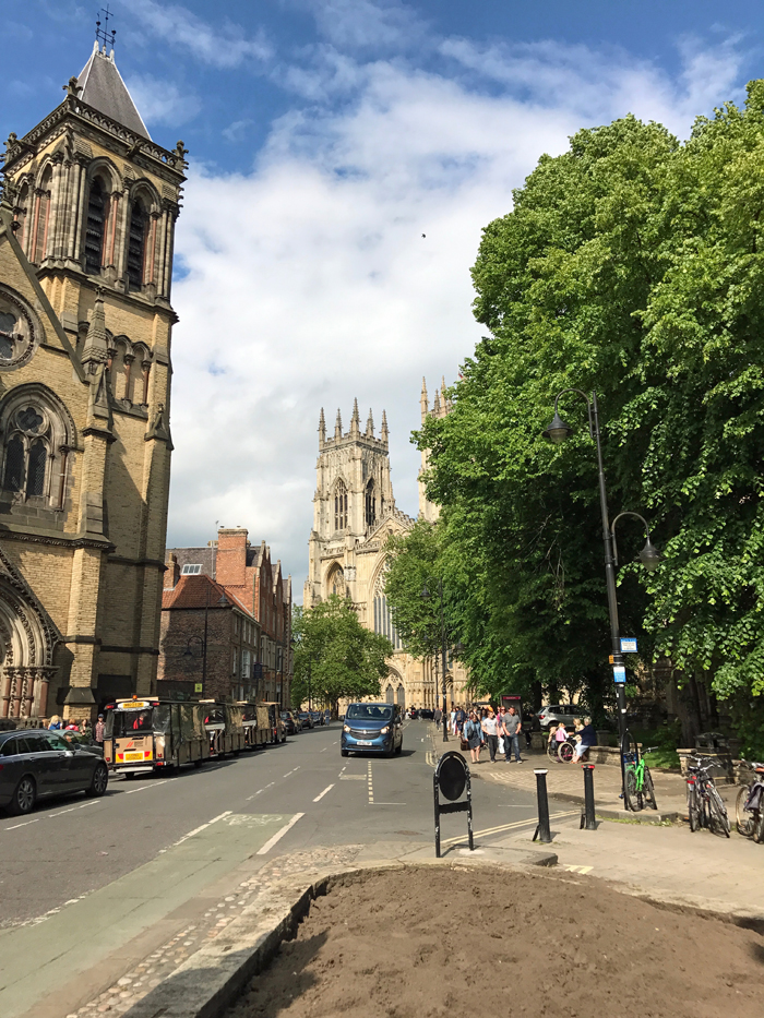 A group of people walking down a street near York Minster.