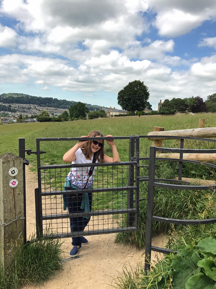 A girl standing by a gate in a field in Bath, UK.