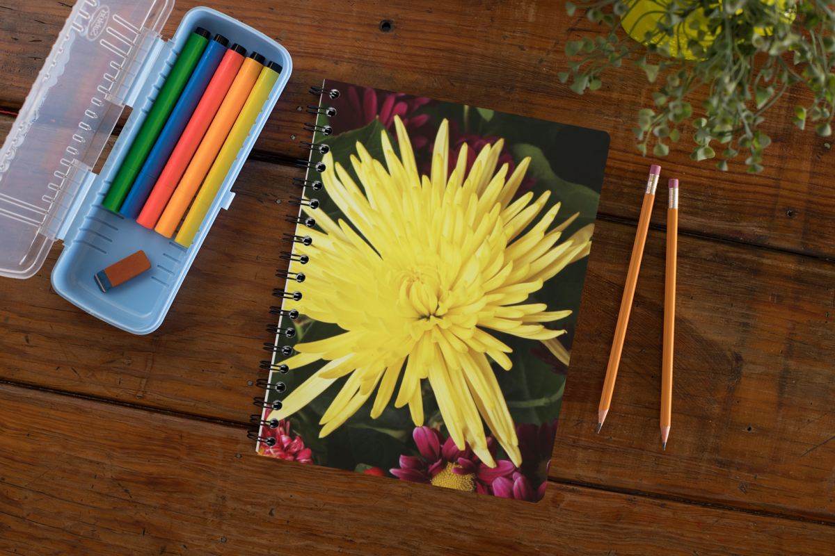 floral planner on table with pencils, plant, and markers.