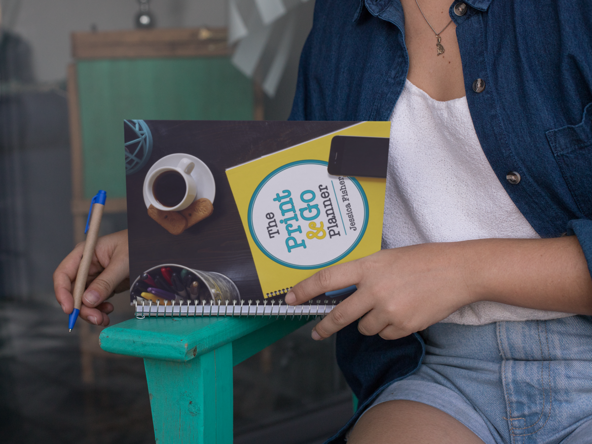 woman holding a planner on the edge of a lawn chair.