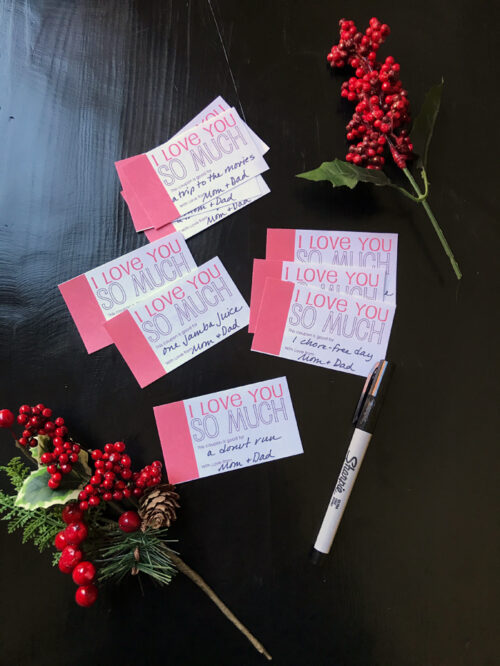 Love You So Much coupons on table with pens and Christmas decor.