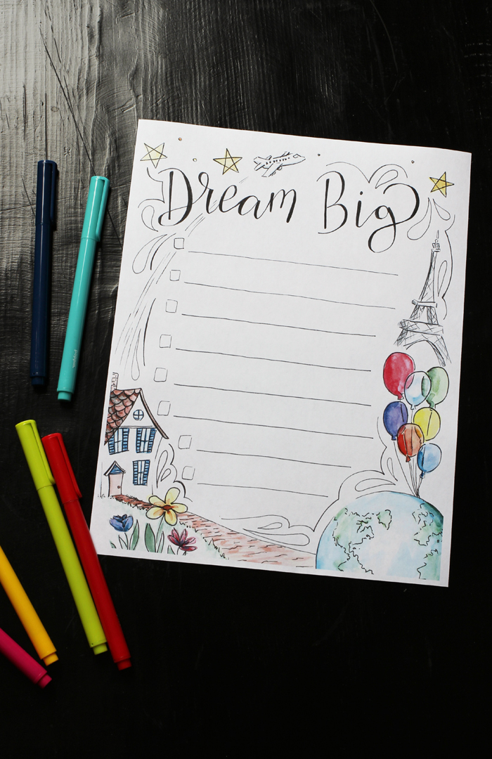 flatlay of dream big worksheet on black table next to colored pens.