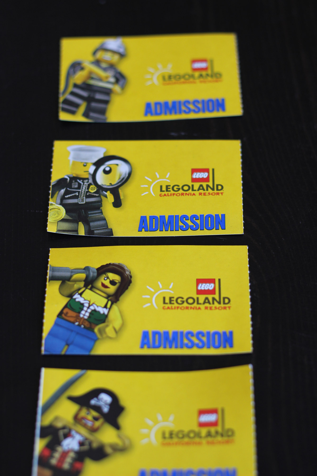four yellow paper legoland tickets lined up on a black table.