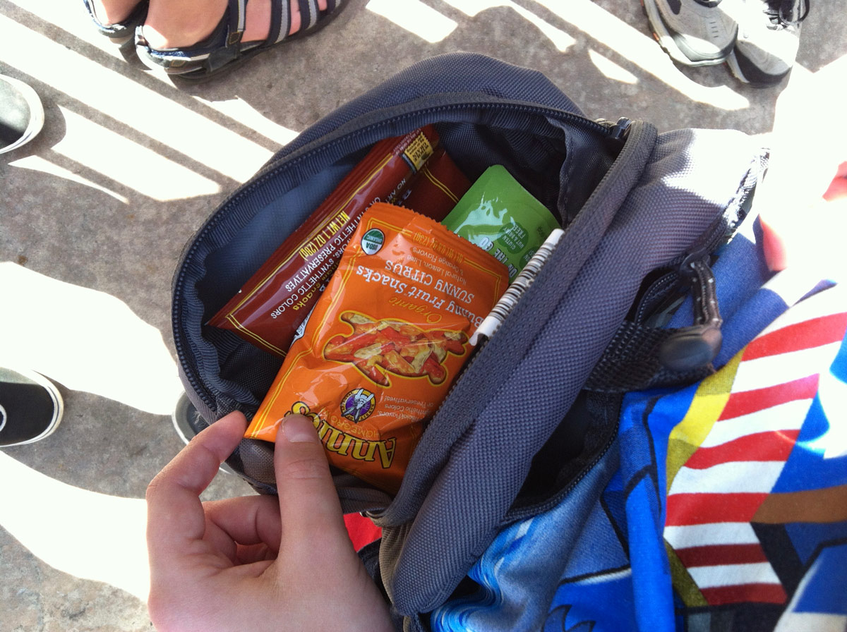 boy reaching into open fanny pack for a snack.