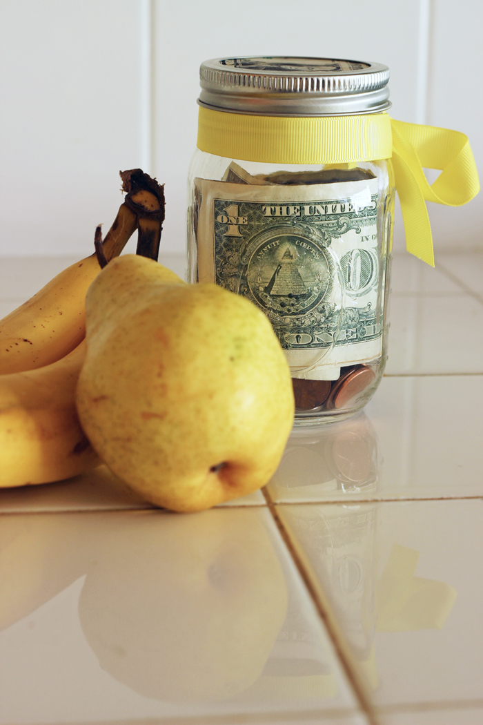 bananas and pear next to jar of money tied with yellow bow